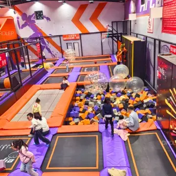Premium custom playground supplier designs minimalist Morandi play areas with combined trampolines, slides, climbing walls and ninja courses.
